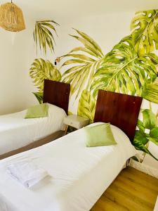 2 camas en una habitación con plantas verdes en Le Cheval Blanc, en Jargeau