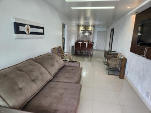 uma sala de estar com um sofá e uma sala de jantar em Frente Mar- 3 quartos- Cond com Piscina e Churrasqueira! em Arraial do Cabo