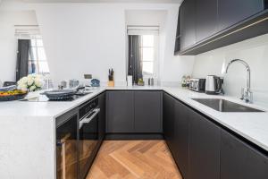 uma cozinha com armários pretos e um lavatório em Marble Arch Penthouse 1 Bed em Londres