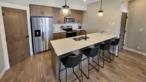 a kitchen with a white counter and a kitchen island with bar chairs at Powder Heights #22 townhouse in Sun Peaks