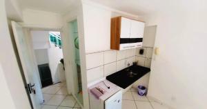 eine kleine weiße Küche mit einem Waschbecken und einem Schrank in der Unterkunft Suíte Privativa com Varanda Ar Cond TV Wi-Fi 201 in Cabo Frio