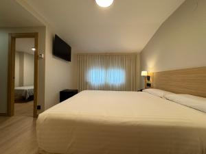 a bedroom with a large white bed and a window at Hotel Europa in Arteixo