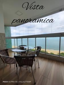 een tafel en stoelen in een kamer met uitzicht op de oceaan bij Ap de Frente para o Mar de Itaparica in Vila Velha
