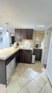a kitchen with brown cabinets and a tile floor at 2 Bedroom Basement Suite in the heart of Laval in Laval