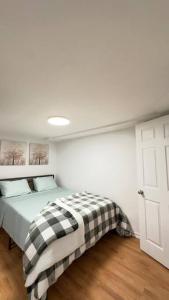 a bedroom with a bed with a checkered blanket on it at 2 Bedroom Basement Suite in the heart of Laval in Laval