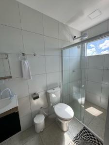 a bathroom with a toilet and a glass shower at Pousada Hércules Beach Paradise in Maragogi