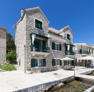 a stone house with tables and chairs in front of the water at Villa Columba - 4 Star Deluxe Apartments - Sea-Front & Panorama View in Makarska