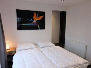 een wit bed in een slaapkamer met een schilderij aan de muur bij Holiday home with motorboat in Olburgen