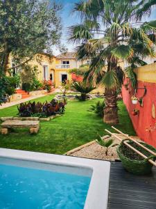 a backyard with a swimming pool and a palm tree at LA BERGERIE DOUCEUR AUBORD in Aubord