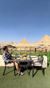 Solima pyramids inn في القاهرة: رجل يجلس على طاولة عليها طعام