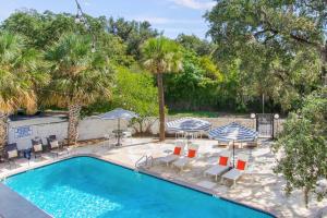 a pool with chairs and umbrellas and palm trees at HUGE outdoor patio with Pool and BBQ - Sleeps 19 in Austin