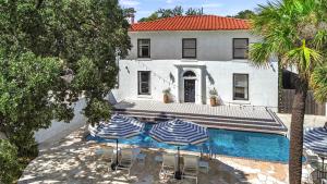 a house with a swimming pool and two umbrellas at HUGE outdoor patio with Pool and BBQ - Sleeps 19 in Austin