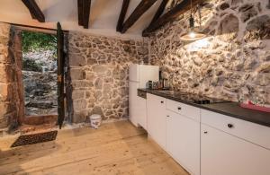 a kitchen with white cabinets and a stone wall at Apartments with parking space Janjina, Peljesac - 21984 in Janjina