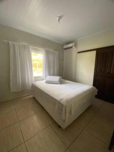ein Schlafzimmer mit einem weißen Bett und einem Fenster in der Unterkunft casa do lago, paz e sossego. in Guaramirim