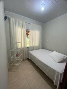 ein Schlafzimmer mit einem weißen Bett und einem Fenster in der Unterkunft casa do lago, paz e sossego. in Guaramirim