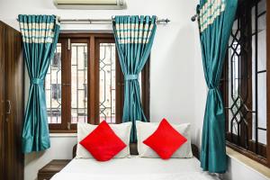 Cette chambre dispose d'un lit avec des oreillers rouges et de fenêtres. dans l'établissement OYO Flagship Shraddha Residency 2, à Kolkata