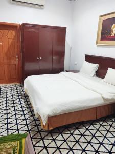 a bedroom with a large bed with a wooden headboard at منتجع الريحانه فلة رقم ٢ in Al Wahţ