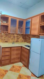 a kitchen with a white refrigerator and wooden cabinets at منتجع الريحانه فلة رقم ٢ in Al Wahţ
