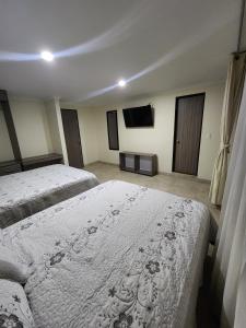 a bedroom with two beds and a flat screen tv at HOTEL CASA MARED Corferias-Embajada Americana in Bogotá