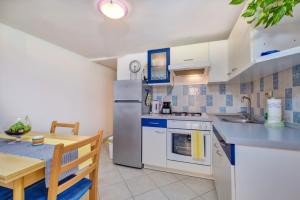a kitchen and dining room with a table and a refrigerator at Apartments by the sea Martinscica, Cres - 22582 in Martinšćica
