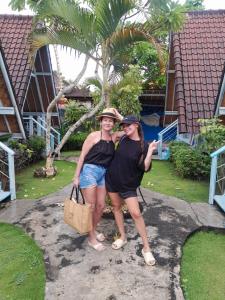 Dos mujeres posando para una foto frente a una casa en D'Yuki Huts Lembongan, en Nusa Lembongan
