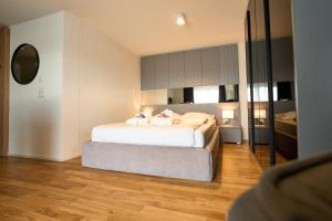 Schlafzimmer mit einem weißen Bett und einem Spiegel in der Unterkunft Cartea Apartments Zürich Airport in Opfikon