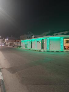 a building with blue lights on the side of a street at منتجع الريحانه فلة رقم ٢ in Al Wahţ
