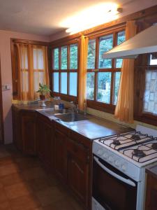 a kitchen with a sink and a stove and windows at Hospedaje BRC in San Carlos de Bariloche