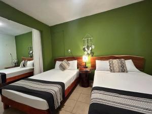 een slaapkamer met 2 bedden en groene muren bij Hotel Koox Jool Bacalar in Bacalar