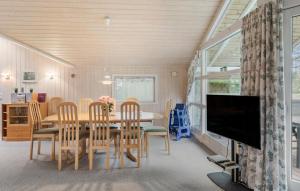 a dining room with a table and chairs and a tv at Holiday Home Ll Strandstræde Dannemare V in Dannemare