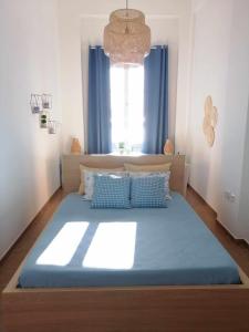 a bedroom with a bed with blue sheets and a window at Aegina Port Apt 4 in Aegina Town