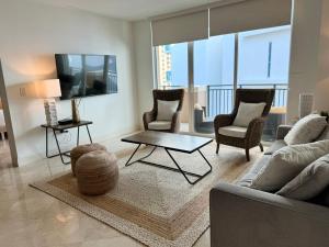 een woonkamer met een bank en stoelen en een tv bij The King David Condos in Miami Beach