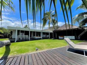 ein Haus mit einer Holzterrasse mit einem Stuhl und einem Hof in der Unterkunft Taunoa House - Family seaside house in Papeete with HS Wifi in Papeete