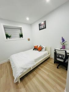 a white bedroom with a bed and a table at Sweet home in Surrey