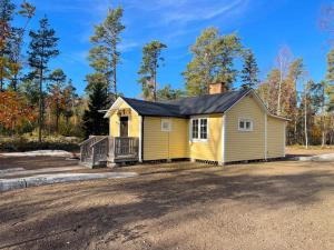 una casa amarilla con porche en la entrada en Holiday home NORRTÄLJE VI en Norrtälje