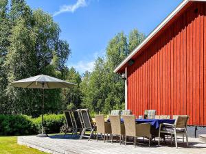 una mesa con sillas y una sombrilla junto a un granero rojo en Holiday home ÅBY, en Åby