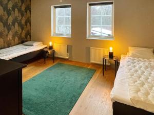 a room with two beds and a green rug at 5 star holiday home in HÖÖR-By Traum in Höör