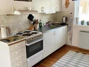 La cuisine est équipée de placards blancs et d'un four avec plaques de cuisson. dans l'établissement Holiday home SUNNE IV, à Sunne