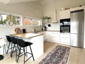 Holiday home UDDEVALLA XIX في Sundsandvik: مطبخ مع دواليب بيضاء وجزيرة مطبخ مع كراسي بار