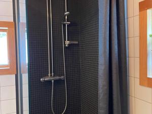 - une douche avec du carrelage noir et un rideau de douche dans l'établissement Holiday home GRYTHYTTAN, à Grythyttan