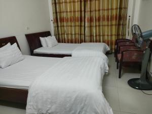 um quarto de hotel com três camas e uma cadeira em khach san viet uc em Vinh