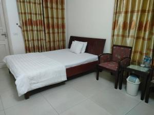 een kleine slaapkamer met een bed en een stoel bij khach san viet uc in Vinh