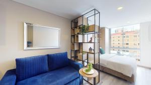 a living room with a blue couch and a bed at Horizon 85 Lofts Zona T in Bogotá