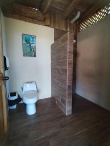 a bathroom with a toilet and a tile wall at Cabaña Vistas Paraíso in La Suiza