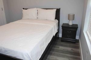 a bedroom with a white bed and a night stand at The Lovely Suite - 1BR close to NYC in Paterson