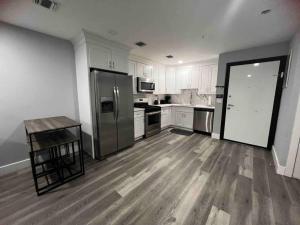 una cocina con armarios blancos y electrodomésticos de acero inoxidable en The Lovely Suite - 1BR close to NYC en Paterson