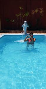 a boy in a swimming pool with a dolphin in the water at Casanostra44 in Genipabu