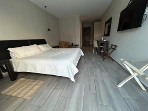 1 dormitorio con cama blanca y suelo de madera en Suites Athos4 en Cancún