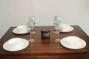 una mesa de madera cubierta con platos blancos y copas de vino en The Charming Suite - 1BR close to NYC, en Paterson
