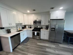 una cocina con armarios blancos y electrodomésticos de acero inoxidable en The Charming Suite - 1BR close to NYC, en Paterson